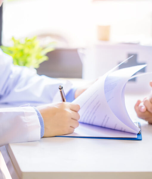 Doctor man consulting patient while filling up an application form at the desk in hospital. Medicine and health care concept